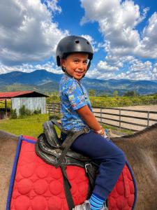 a young boy sitting on top of a horse at El Caney Experiences in Armenia