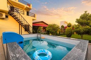 a swimming pool in front of a house at Ramashray - Mud House Living in Haldwāni