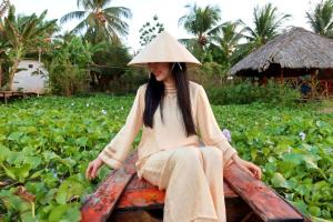 a woman wearing a hat sitting on a bench at Que Nha Homestay in Ấp Chợ (2)