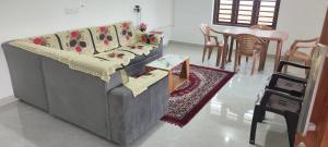 a living room with a couch and a table and chairs at Ithal Villa - Home Stay in Wayanad
