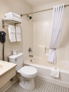a white bathroom with a toilet and a bath tub at Super 8 by Wyndham Canandaigua in Canandaigua +10 photos