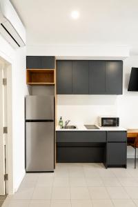 a kitchen with a refrigerator and a sink at The Park OASIS Burwood in Sydney