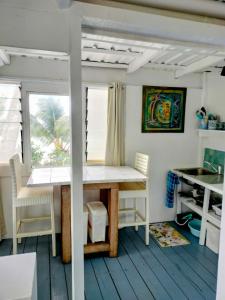 a table and chairs in a room with a window at Heron's Reef Beach Shack Matavera in Matavera +22 photos