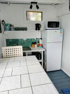 a small kitchen with a white refrigerator and a table at Heron's Reef Beach Shack Matavera in Matavera