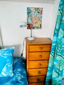a bedroom with a bed and a dresser with a lamp on it at Heron's Reef Beach Shack Matavera in Matavera