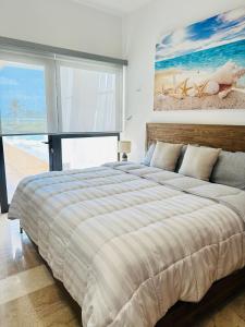 a bedroom with a large bed with a painting on the wall at Navela oceanfront apartment in Telchac Puerto +41 photos