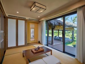 a living room with a table and a large window at Kobi Onsen Resort Hue, Affiliated by Meliá in Hue