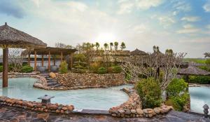 a swimming pool in a yard with a resort at Kobi Onsen Resort Hue, Affiliated by Meliá in Hue