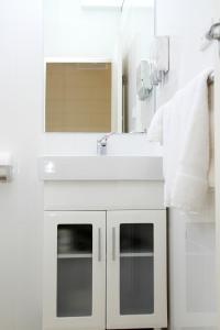 Baño blanco con lavabo y espejo en Renmark Motor Inn, en Renmark