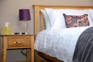 a bedroom with a bed and a night stand with a lamp at Cedar Tree Cottage in Clocaenog