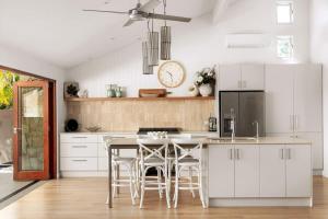 a kitchen with white cabinets and a table with stools at Sunshine Beach Retreat, Pool, Backyard in Sunshine Beach