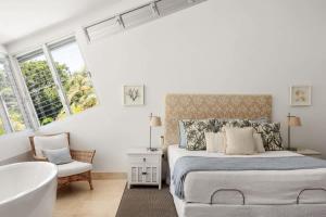 a white bedroom with a bed and a bath tub at Sunshine Beach Retreat, Pool, Backyard in Sunshine Beach +14 photos