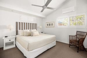 a white bedroom with a bed and a ceiling fan at Sunshine Beach Retreat, Pool, Backyard in Sunshine Beach