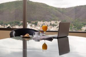 a table with a laptop and a glass of orange juice at Hotel Alejandro I, Affiliated by Meliá in Salta