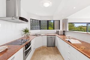 a kitchen with white cabinets and a wooden counter top at Beach Luxury, Ocean Views & Pool in Noosa Heads