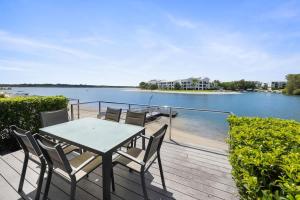 a table and chairs on a deck next to the water at Driftwood 6 Private Beach Stay in Noosaville