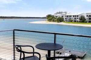 a table and chairs on a balcony overlooking a body of water at Driftwood 6 Private Beach Stay in Noosaville