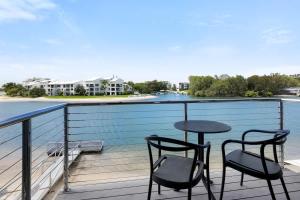 a balcony with two chairs and a table with a view of the water at Driftwood 6 Private Beach Stay in Noosaville