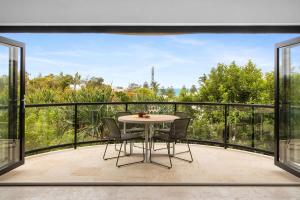 a patio with a table and chairs on a balcony at Beach Luxury, Ocean Views & Pool in Noosa Heads