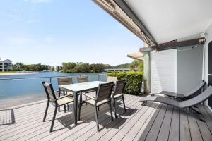 a deck with a table and chairs and the water at Driftwood 6 Private Beach Stay in Noosaville +13 photos