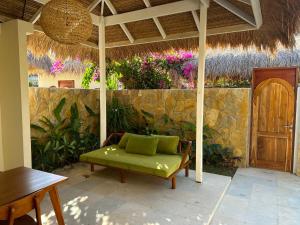 a patio with a green couch and a stone wall at Seraya Villas in Kuta Lombok