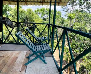 two blue chairs sitting on a porch with trees at Green Tree House Yala in Yala +20 photos