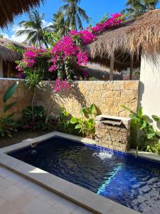 a swimming pool in front of a house with pink flowers at Seraya Villas in Kuta Lombok +12 photos