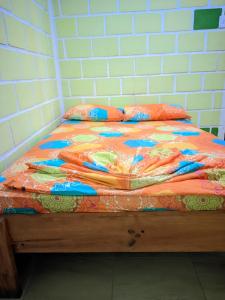 a bed with a colorful comforter and pillows at hotel con piscina Ladrilleros in Ladrilleros +24 photos