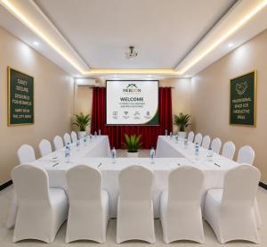 a conference room with a large white table and white chairs at NEBCON Executive Lodge in Kitwe