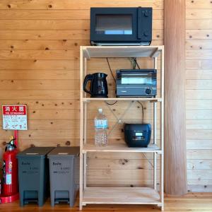 a book shelf with a microwave and a tv at Karin in Minami Aso