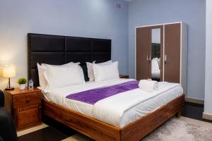 a bedroom with a large bed with a black headboard at NEBCON Executive Lodge in Kitwe +23 photos
