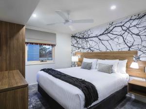 a bedroom with a bed with a tree mural on the wall at The Sebel Pinnacle Valley in Merrijig