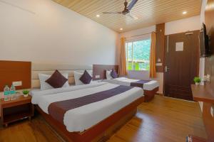 a hotel room with two beds and a window at Prideinn Luxury Resort in Rishīkesh