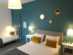 a bedroom with two beds with blue walls and mirrors at Hotel Saint-Michel in Dinard