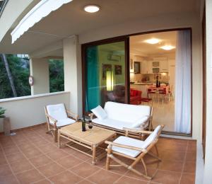 a patio with white chairs and a table on a porch at Residence Apartments Anamaria in Podstrana
