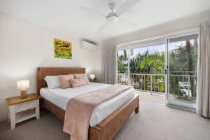 a bedroom with a bed and a large window at Moondarah: Pet-Friendly Escape in Noosa Heads