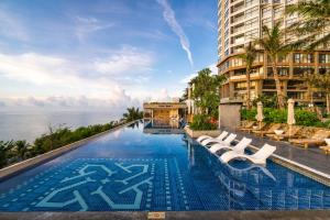 a pool at a hotel with chairs and the ocean at Mandala Pearl Resort in Phan Thiet