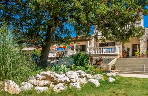 een huis met een tuin met rotsen ervoor bij Apartments Lili in Medulin