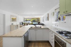a kitchen with white cabinets and a large counter top at Noosa Haven Apt 6 Riverside Retreat in Noosaville