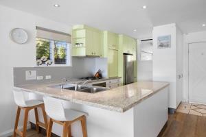 a kitchen with a sink and two white bar stools at Noosa Haven Apt 6 Riverside Retreat in Noosaville