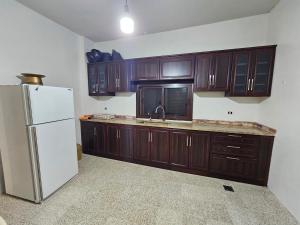 a kitchen with wooden cabinets and a white refrigerator at Moufid villa in Al Mīdān