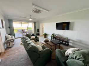 a living room with green couches and a television at Backyard Bliss in Waikerie