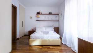 una camera da letto con letto, lenzuola bianche e pavimenti in legno di Italianway-Cirillo a Milano