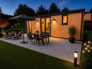 a patio with a table and chairs and an umbrella at Hassberge Chalets in Kirchlauter