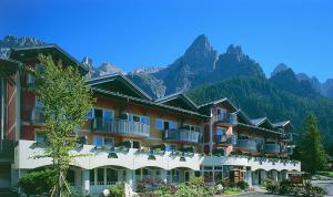 um grande edifício com montanhas ao fundo em Sporting Clubresidence em San Martino di Castrozza