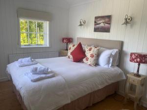 a bedroom with a bed with white sheets and pillows at Roberts’ Cottage in Westport