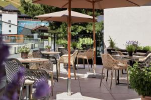 an outdoor patio with tables and chairs and umbrellas at Edelweiss echt-charmant in Sölden