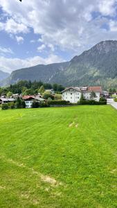 a large field of green grass with houses and mountains at Gästehaus Binderlehen in Schönau am Königssee