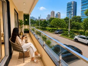 a woman sitting in a chair taking a picture of a city at Lime Tree Hotel Golf Course Extension Nearby Grand Hyatt Gurgaon in Gurgaon