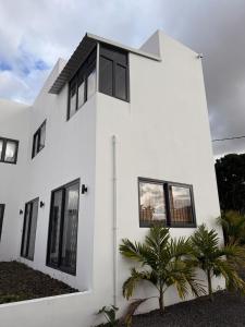 a white house with black windows and palm trees at La Casa Floréal in Curepipe